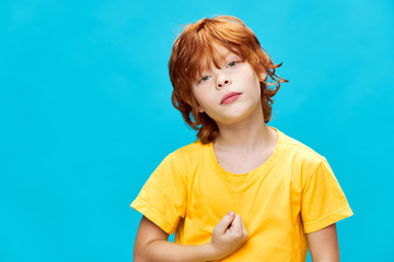 child in a yellow t-shirt clenched his hand into a fist background