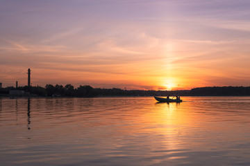 Fototapeta na wymiar Rowing boat at sunset on Lake Senezh in the city of Solnechnogorsk