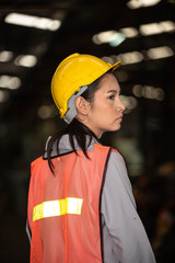 Portrait of young beautiful Asian woman technician or industrial worker with hard hat and vest working machine in Factory of manufacturing place and Bokeh on Background
