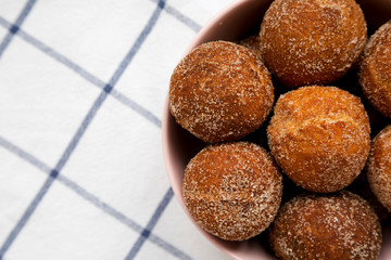 Homemade Fried Donut Holes in a pink bowl on cloth, top view. Flat lay, overhead, from above. Copy...