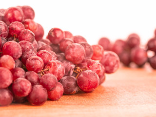 Red ripe grapes with water spray to freshness after harvesting on wooden background.