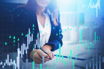 Woman writing in office, financial graph