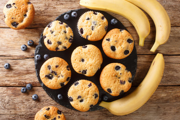 Freshly baked muffins with blueberries and bananas close-up on a slate board on the table. horizontal top view from above
