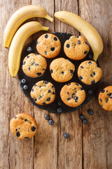 Fresh muffins with blueberries and bananas close-up on a slate board on the table. vertical top view from above