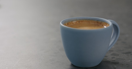 blue cup with fresh espresso on concrete surface