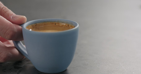 man hand take blue cup with fresh espresso on concrete surface