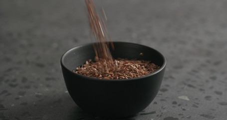 flaxseed falling into black bowl on terrazzo countertop