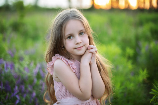 Close-up portrait child praying. Little girl hand praying, hands folded in prayer concept for faith, spirituality and religion. Cute smiling baby girl with long hair outdoors. childhood. Copy space. 