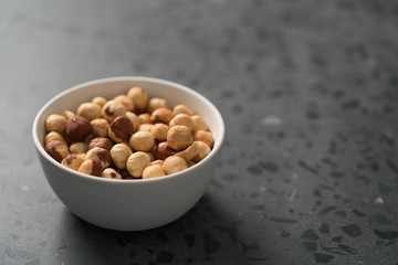 roasted hazelnuts in white bowl on concrete background