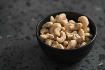 roasted cashew in black bowl on terrazzo countertop