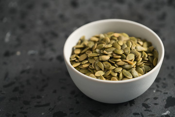 pumpkin seeds in white bowl on terrazzo countertop