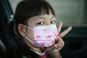 Little child girl wearing face mask  to prevent Corona virus or Covid-19 in the car.