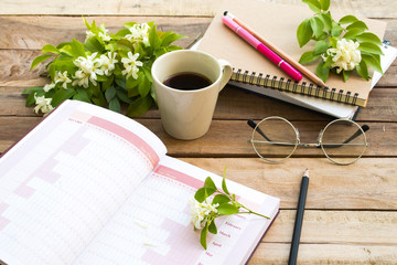 notebook project year planner for business work with hot coffee espresso ,white flowers jasmine arrangement flat lay style at office desk 