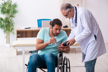 Experienced doctor and young male patient in wheel-chair