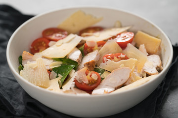 Fresh caesar salad with chicken and cherry tomatoes in white bowl