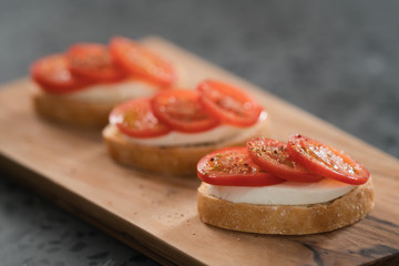 Simple bruschetta with tomatoes and mozzarella on olive wood board