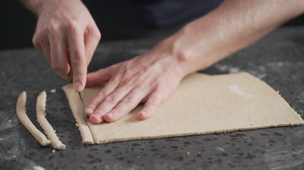 man cutting flat dough with knife