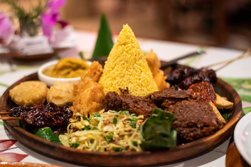 Freshly cooked dinner platter with decoration of spicy meat, rice and green vegetables and sauce in a restaurant in Bali