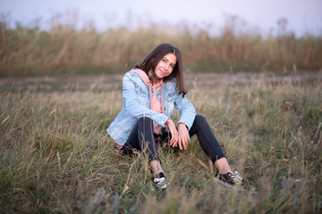 Young European woman or student is sitting  in the evening in a field