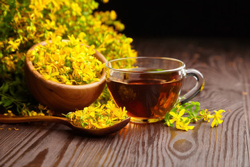 Herbal tea of Hypericum perforatum or St johns wort medicinal herb with fresh flowers in wooden...