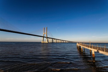 Obraz premium The Vasco da Gama Bridge is a cable-stayed bridge flanked by viaducts and spans the Tagus River in Parque das Nações in Lisbon, the capital of Portugal. It is the longest bridge in the European Union