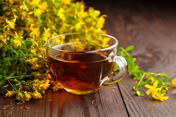 Cup with Hypericum perforatum, St Johns wort or tutsan plant drink with fresh flowers.
