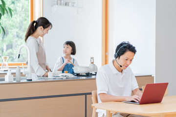 家で仕事をする父親　料理をする母子