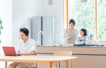 家で仕事をする父親　料理をする母子