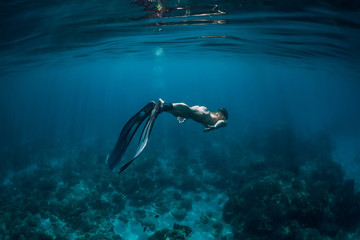 Fototapeta na wymiar Woman free diver with fins swim underwater in blue ocean