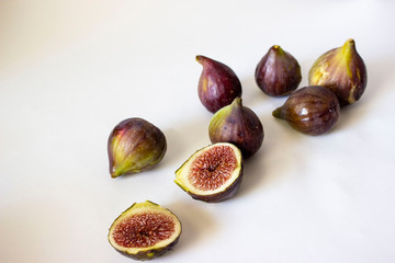 Ripe figs, purple green. Whole fruits and cut with red flesh and seeds. Grey-blue background.