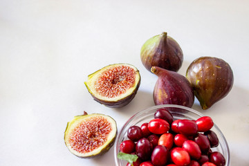 Ripe figs, purple green, whole fruits and cut with red flesh with seeds.Dogwood in a glass bowl Gray and blue background.