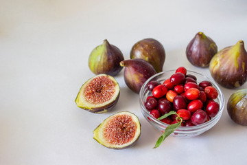 Ripe figs, purple green, whole fruits and cut with red flesh with seeds.Dogwood in a glass bowl Gray and blue background.