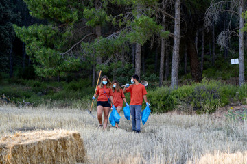 Young janitors working in the woods collecting garbage.