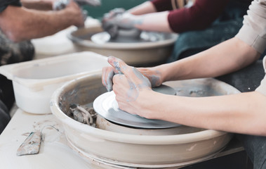Guy molding clay pot craftsman teaching pottery woman wheel crafts workshop