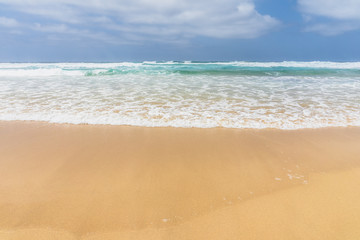 Fototapeta na wymiar View of the ocean waves, sandy beach and sky.