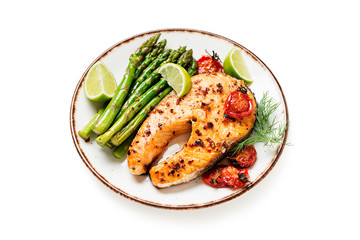 Baked salmon steak garnished with asparagus and tomatoes . isolated on white background
