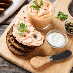 Smoked salmon and soft cheese spread  pate with brown bread and capers on a wooden background.