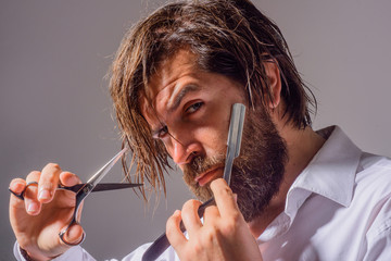 Handsome bearded man with barber tools. Professional beard care. Barber razor. Scissors....