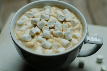 Cup of coffee with marshmallow on books on a wooden background.Slow liwing style background