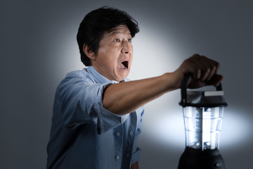 暗闇で何かに驚くランタンを持った中年男性