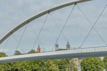 Close-up of the arch of the High Bridge over the Maas river with the towers of the Basilica of Our Lady and the red tower of the Church of Saint John in the background, Maastricht, Netherlands