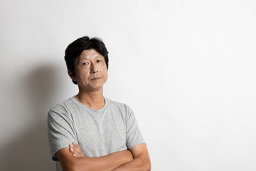 腕を組むTシャツ姿の中年男性