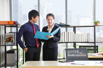 Asian business manger and his female secretary wearing formal suit are discussing over the annual...