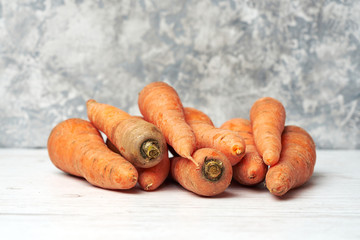 Closeup heap of fresh raw carrots on a light wooden table and gray background