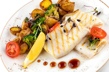 grilled squid with garnish. garnish fried potatoes with vegetables and lemon