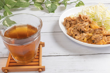 光が差し込むテーブルに置かれた、冷えた麦茶と豚キムチ