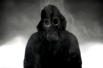 Person wearing a gasmask surrounded by smoke. 