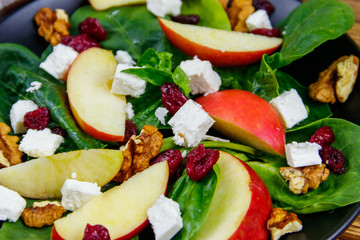 Autumn spinach salad with apple, feta cheese, walnut and dried cranberry. Healthy vegetarian food