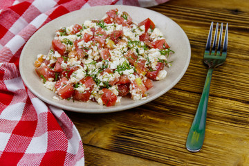 Tasty salad of tomato, cottage cheese, dill and olive oil on wooden table