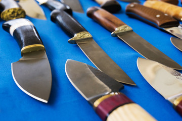 Metal knives with a wooden handle. Handmade steel products on the counter in the store. Production and trade in hazardous items. Close-up